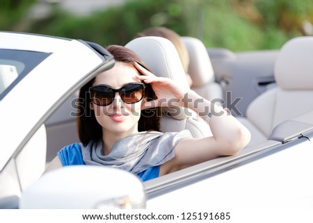 Portrait of dreamy woman wearing sunglasses in the cabriolet and propping her head