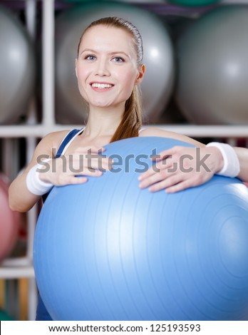 Athletic woman with blue gym ball in fitness gym