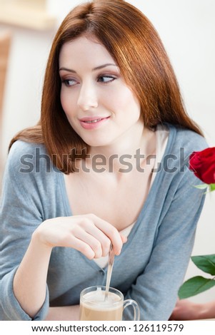 Woman with red rose sitting at the cafe
