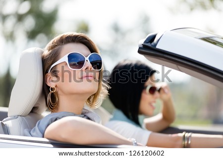 Close up of girls wearing sunglasses in the white car. Little holiday trip of friends