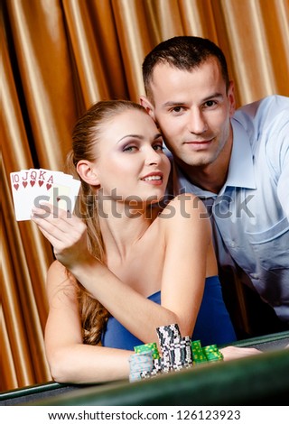 Couple playing poker at the gambling house. Woman keeps cards in hand