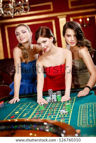 Three women place a bet playing roulette at the casino club