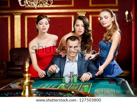 Man surrounded by girls plays roulette at the casino