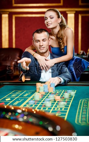 Man embraced by pretty girl throws the chip on the casino table