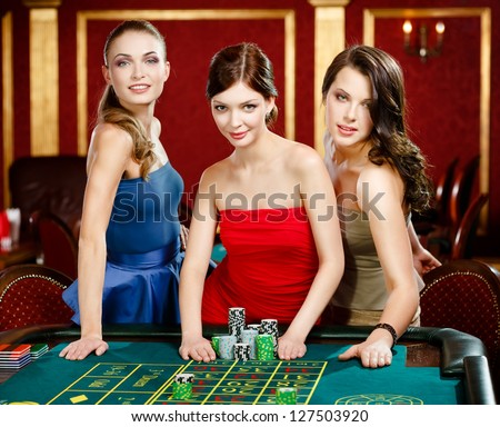 Three women place a bet playing roulette at the casino