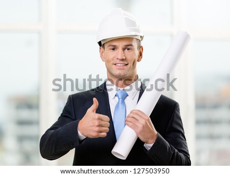 Engineer in white hard hat hands layout and thumbs up. Concept of successful construction