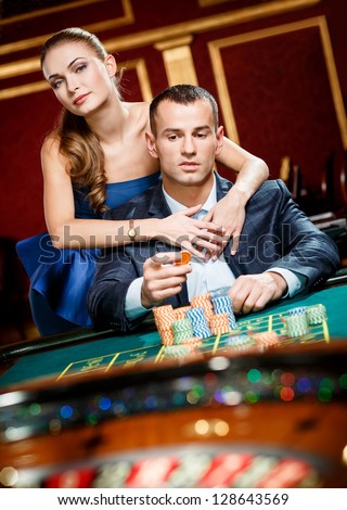 Girl embracing gambler at the roulette table. Player follows the risky game