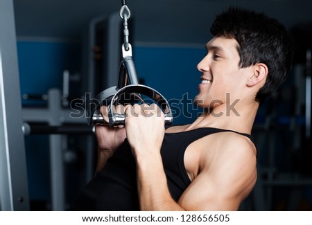 Athletic young man works out on simulator in gym