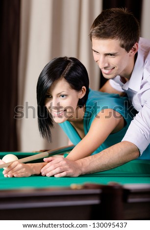 Man teaching young woman to play billiards. Spending free time on gambling