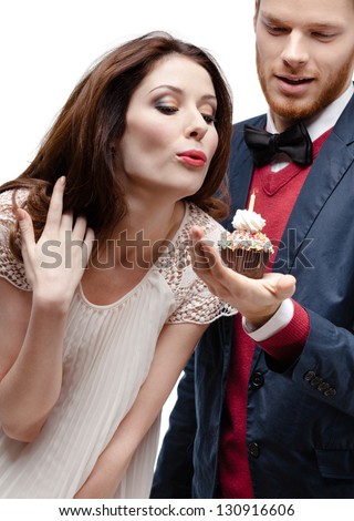Woman puts out candle in the cake that the boyfriend presented to her, isolated on white