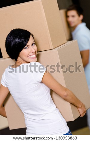 Back view of woman carrying cardboard boxes against the husband while moving to new house