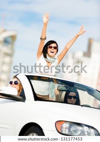 Lovely teenager with her hands up in the car with friends. Girls ride somewhere on vacation