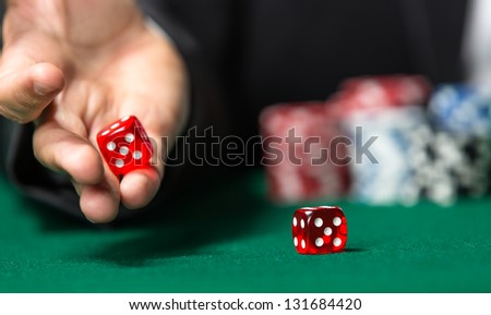 Player throws dices on the poker table. Symbol of addiction to the poker