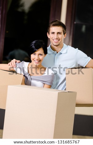 Happy couple carrying pasteboard containers while moving to new house