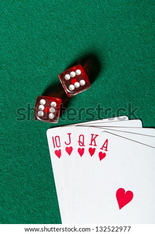 Royal Flush poker card sequence near dices on a green table. Risky entertainment of gambling