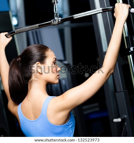 Athletic young woman works out on simulator in gym class