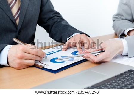 Two business people discuss financial issues sitting at the business table with documents, isolated on white