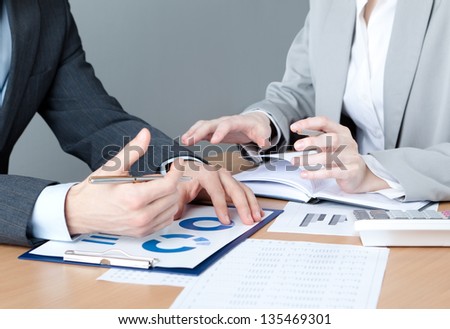 Two business people discuss economic issues sitting at the business table with documents