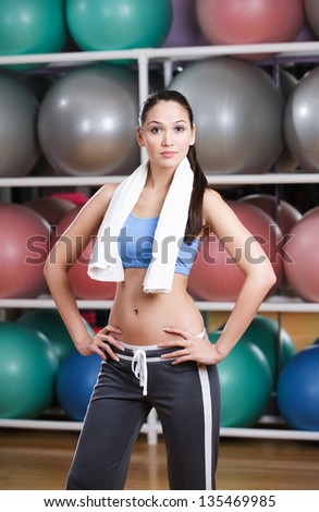 Sportive sexy woman in fitness gym with shelves of gym balls