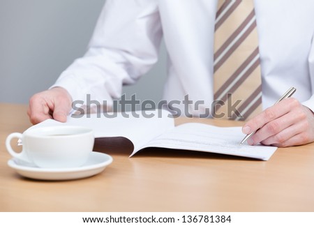 Sitting at the table businessman writing in the notebook