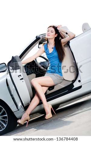 Pretty woman in sunglasses sits in the white car with side door opened