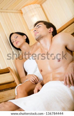 Half-naked man and lady relaxing in sauna. Concept of self-care, health and relaxation