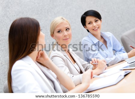 Female colleagues discuss business plan sitting at the meeting hall. Team success