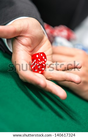 Player throws dices on the poker table. Challenge to the casino
