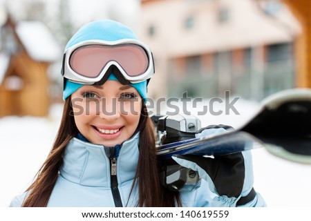 Close up of female wearing sports jacket and goggles who hands skis
