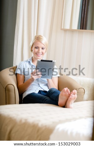 Girl sitting on the sofa with silver pad. Concept of education and online communication
