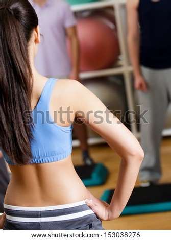 Sexy female coach demonstrates exercises to her group at the gym in a fitness class