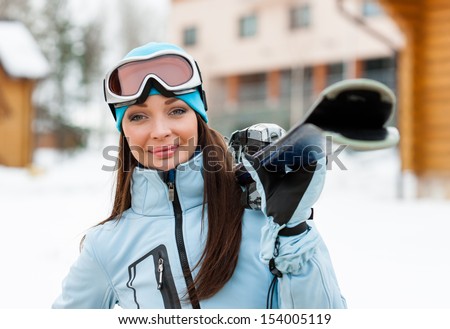 Portrait of woman wearing sports jacket and goggles who hands skis