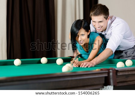 Man teaching girl to play billiards. Spending free time on gambling