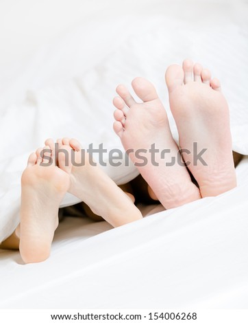 Close up of two pairs of feet of the couple next to each other in bed