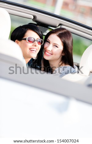 Two happy girls sitting in the car look back and have fun while having little car trip