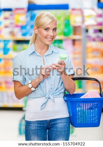 Girl at the shop with cosmetics in hands going to buy it. Concept of consumerism, retail and purchase