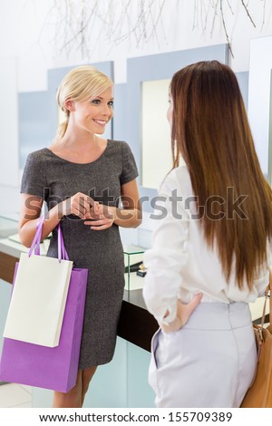 Two girls discuss purchases at jeweler\'s shop. Concept of wealth and luxurious life