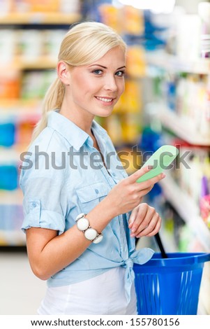 Half length portrait of girl at the store choosing cosmetics among the great variety of products. Concept of consumerism, retail and purchase