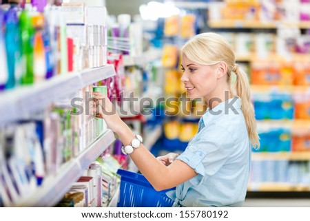 Profile of girl at the shop choosing cosmetics among the great variety of products. Concept of consumerism, retail and purchase