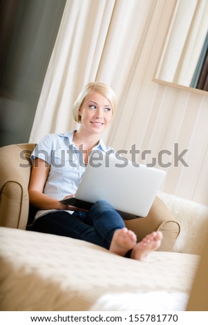 Woman sitting on the couch with silver laptop. Concept of education and online communication