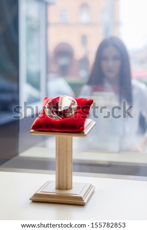 Girl looking at the diamond through the window at jeweler\'s shop. Concept of wealth and luxurious life