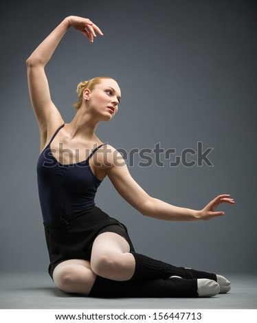 Dancing on the floor ballerina with her hand up, isolated on grey. Concept of elegant art and sportive hobby