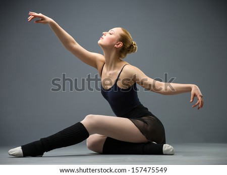 Dancing on the floor ballerina with outstretched arms, isolated on grey. Concept of elegant art and sportive hobby