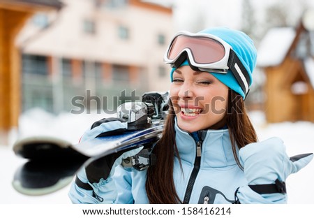 Close up of girl wearing sports jacket and goggles who hands skis and thumbs up