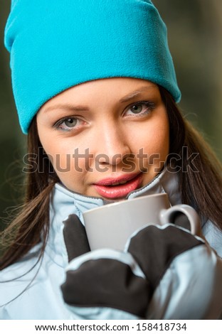 Portrait of female drinking tea and wearing warm clothes outdoors when going in for winter sports