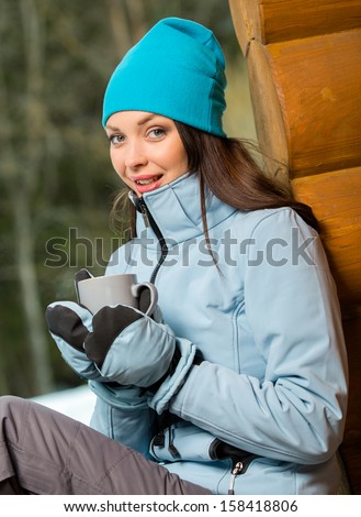 Portrait of girl drinking hot tea and wearing warm clothes outdoors when going in for winter sports