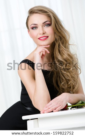 Portrait of woman in black dress leaning at the piano. Concept of music and art