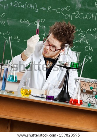 Mad professor examines a beaker in his laboratory