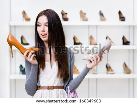 Woman keeps two high heeled shoes in the shopping mall and can\'t choose the one for her