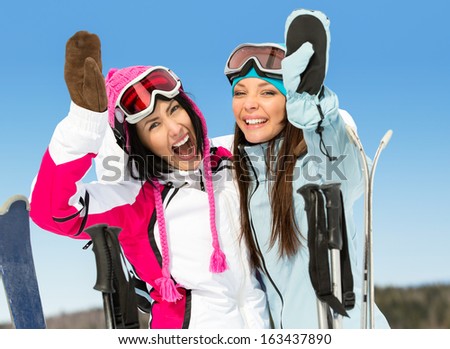 Half-length portrait of two female skier friends with hands up